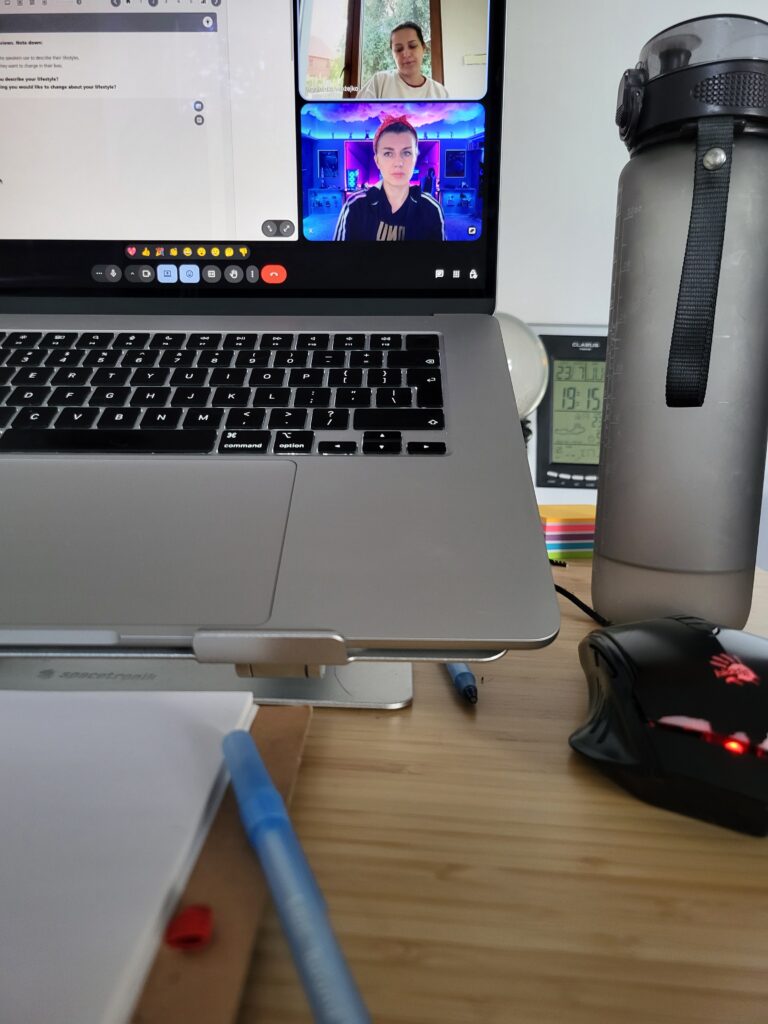 Laptop z widocznymi osobami na spotkaniu przez Google Meet - lekcja angielskiego online dla dorosłych z materiałem audio i video. Uczennica skupiona na zadaniu. Konwersacje z angielskiego połączone z nauką gramatyki.