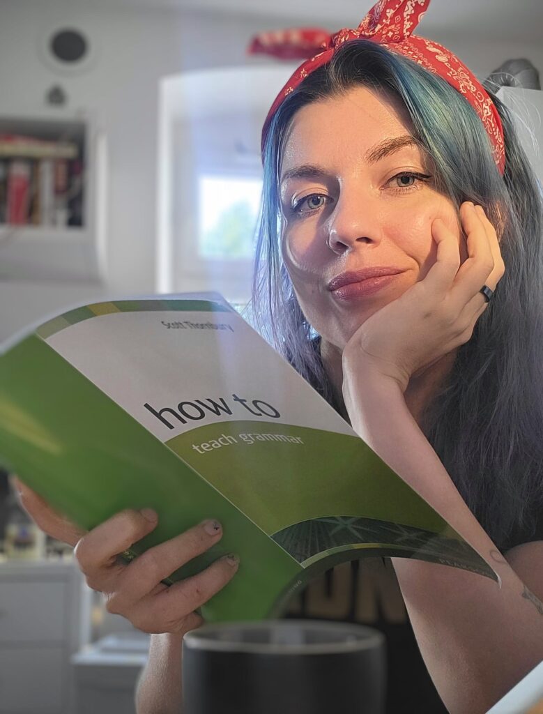 Nauczycielka angielskiego Karo the Tutor (Karolina Warchoł) trzyma książkę o tym jak uczyć gramatyki i uśmiecha się.