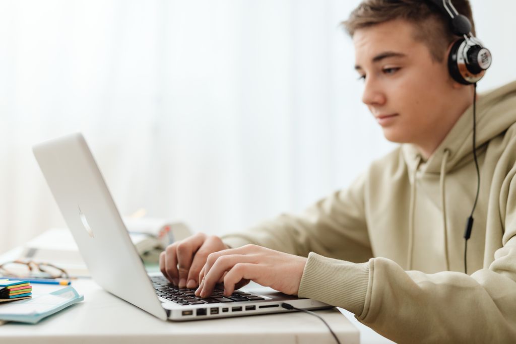 Nastolatek uczy się z laptopa na korepetycjach z angielskiego online.